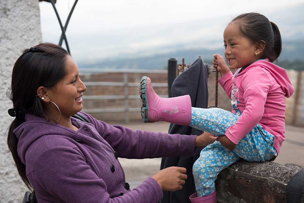 Fernanda's mom helps her with putting on her boots