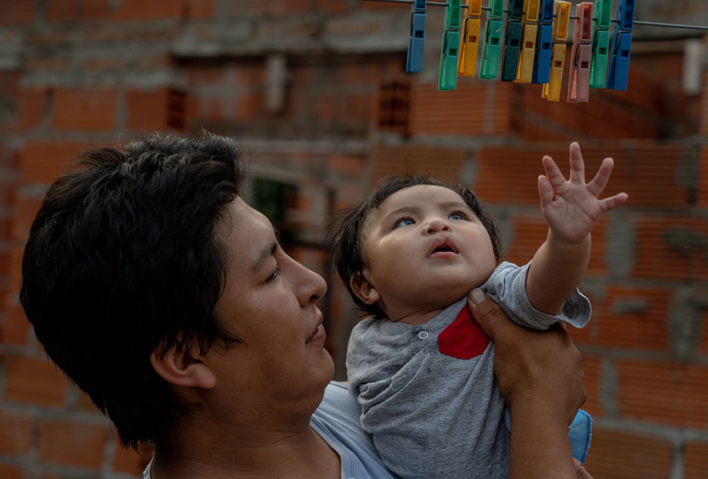 Miguel reaches for clothespins in his father's arms