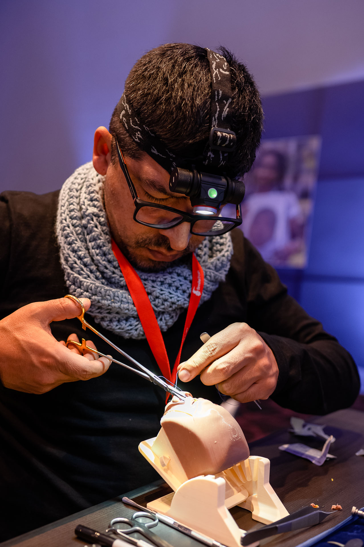 Huáscar Aillón wearing a headlamp sewing medical stitches onto a Simulare cleft model