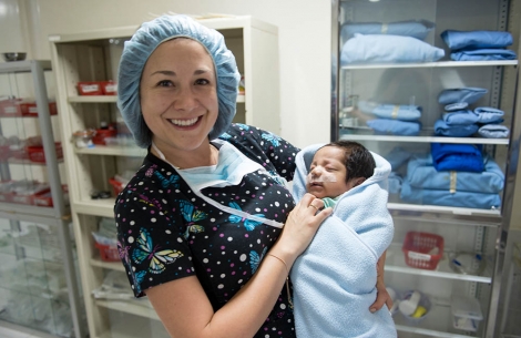 Doctor holds baby after cleft surgery