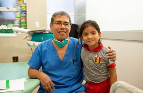 Dr Meza with his arm around a dental patient
