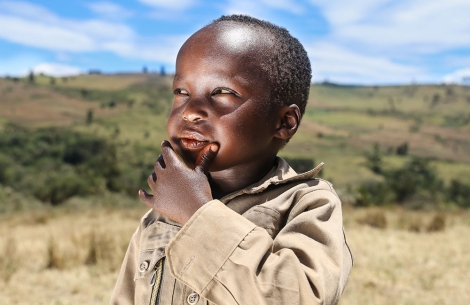 Benjamin thinking in a field in Kenya after his Smile Train-sponsored cleft surgery