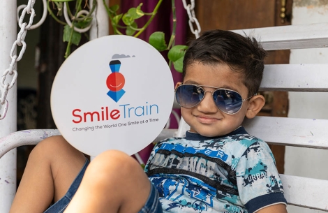 Young patient smiling and holding a Smile Train sign