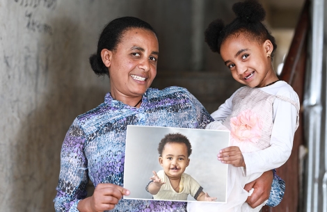 Zinash holding Marsillas and a picture of her before her cleft surgery. Both are smiling