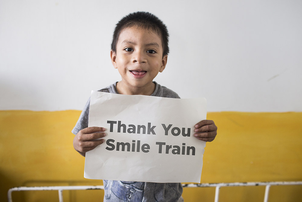 Auner holds a sign that says thank you Smile Train