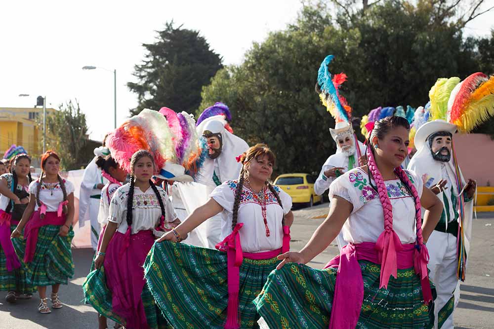 A parade filled with bright colored dresses and costumed men