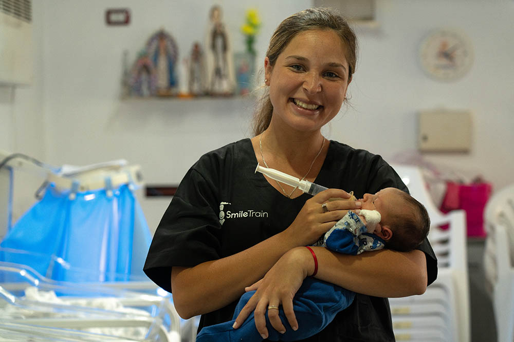 Celeste feeds a small infant with syringe 