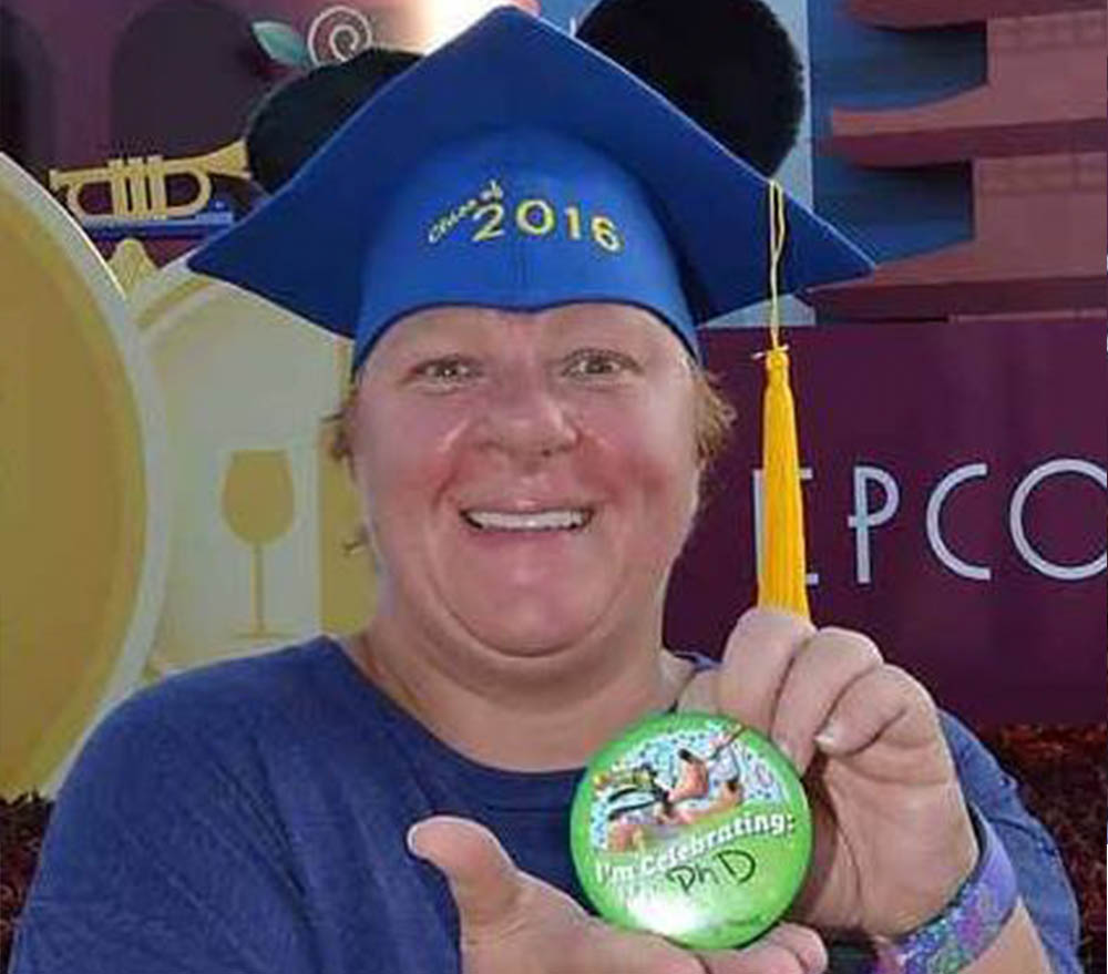 Christine holds up button celebrating her Phd