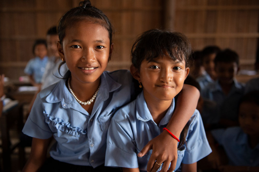 A classmate puts her arm around Samnang at school