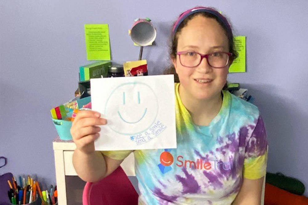 Grace holds up Smile Train social media sign