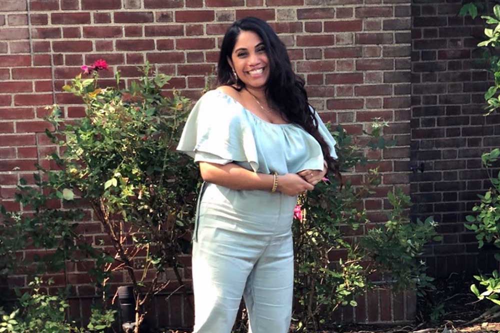 Hema stands in front of a rose bush