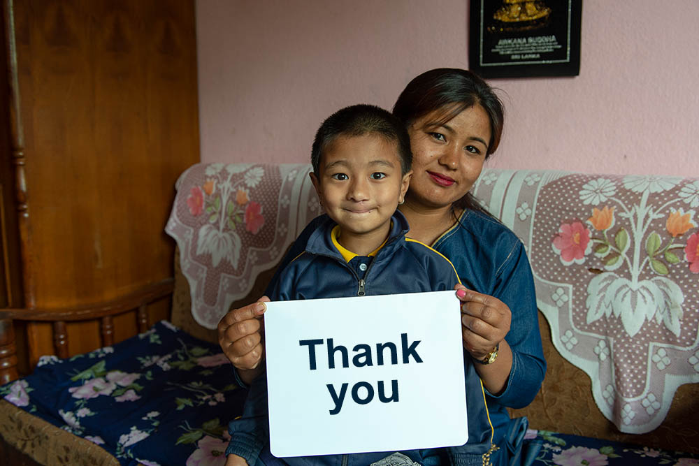 Jenious and his mom hold thank you sign