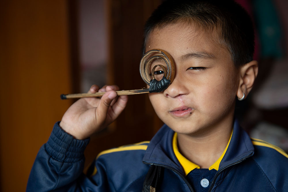 Jenious holds his drum stick to his eye