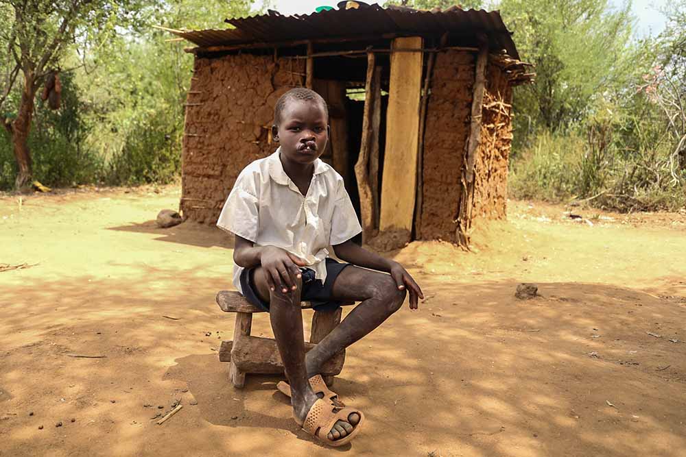 Kamse sits in front of house