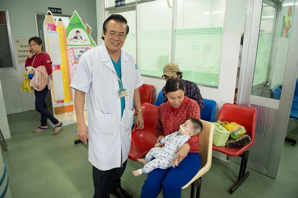 Nguyen Van Dau attends to a baby after cleft surgery