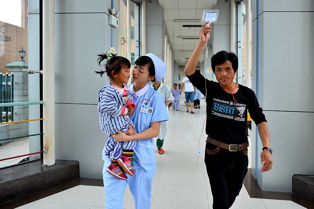 Renpuci in nurses arm on the way to surgery, dad holding iv bag