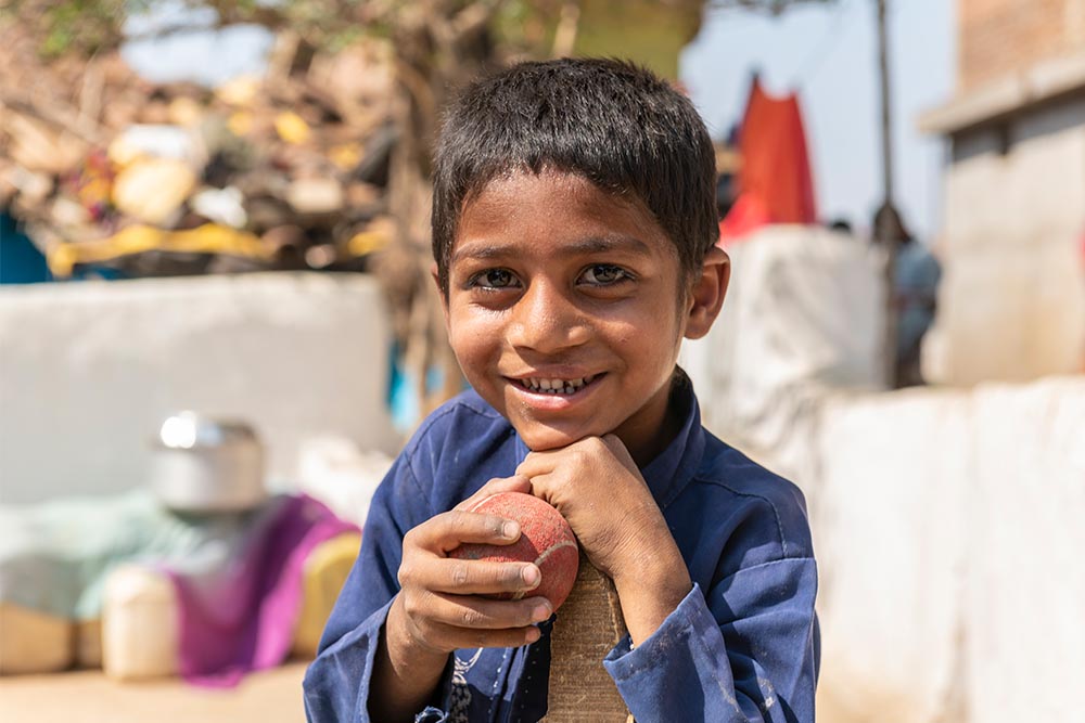 Sahil holds a cricket ball and bat