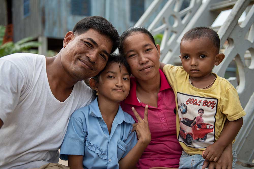 Samnang poses with her family and gives a peace sign with her hand