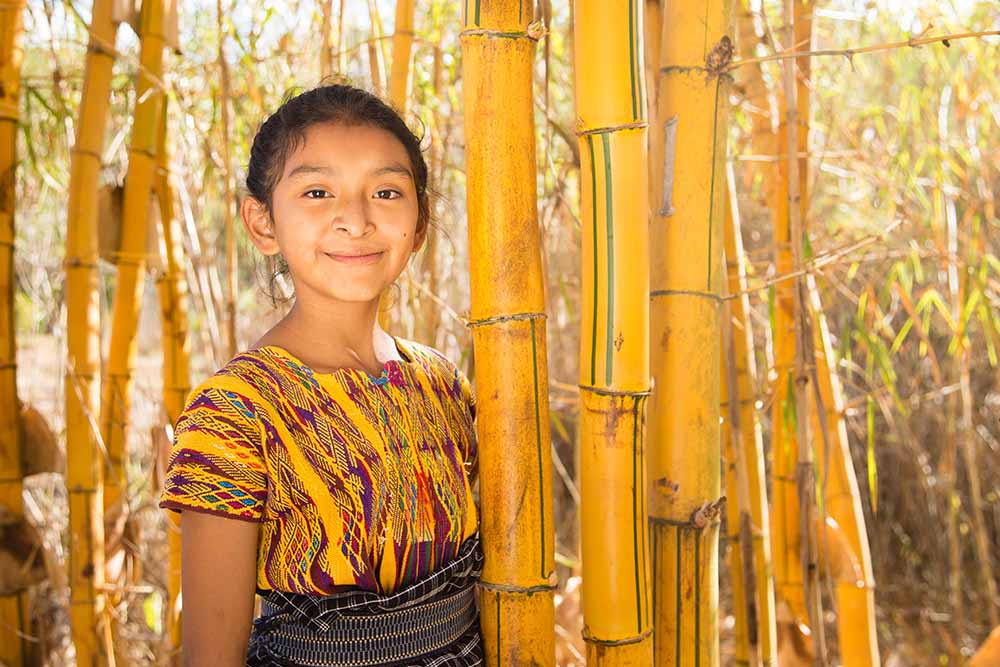 Valery in yellow shirt next to yellow bamboo