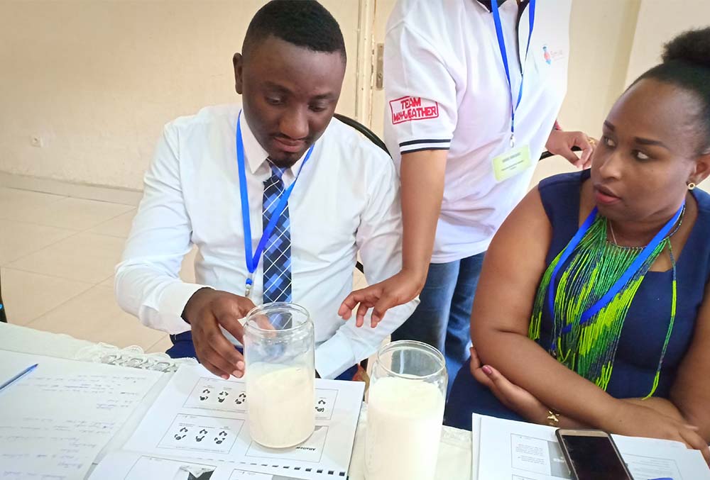 Workshop members look at jars of milk on table