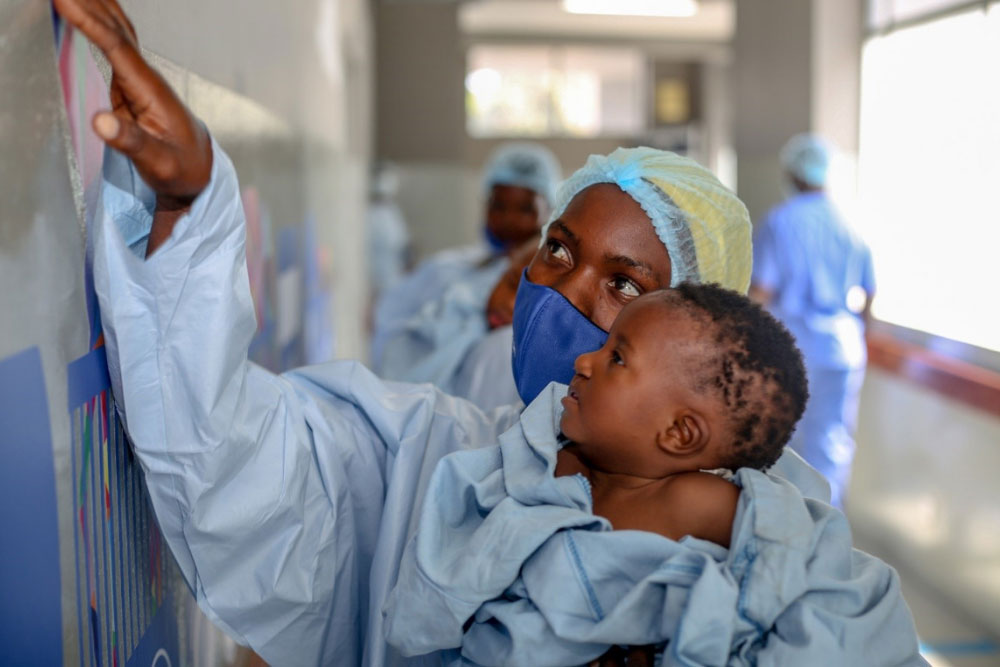 A surgeon shows an infant the new wall designs at BCM in Tanzania