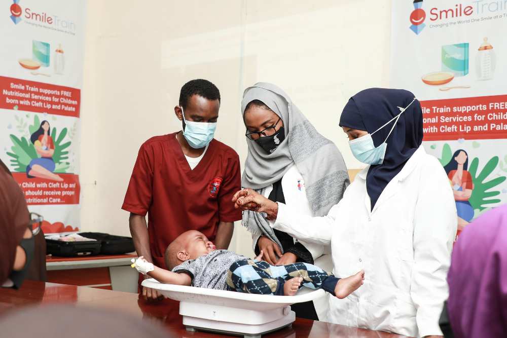 Healthcare workers weighing baby 