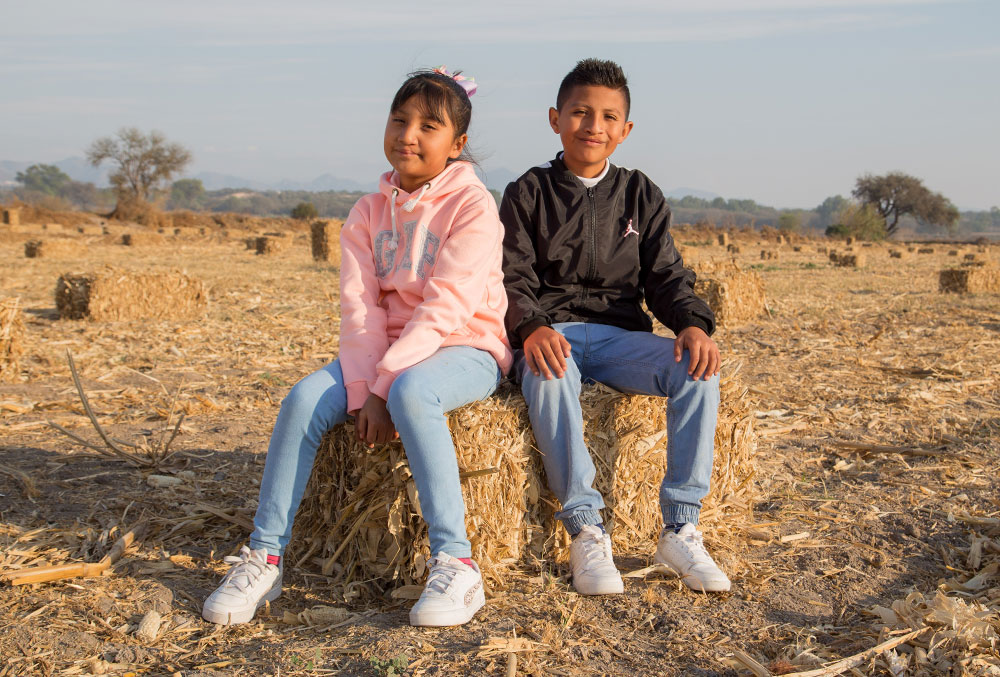 Kendra and Alex sit on a bale of hay