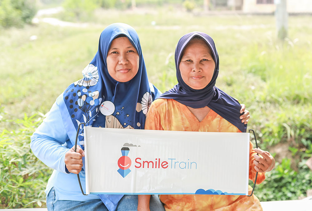 Endang holding a Smile Train banner with another woman