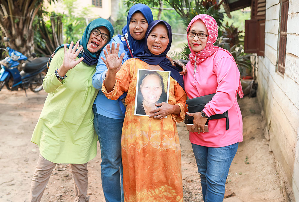 Endang with a patient's family holding a picture of the patient before her free cleft surgery