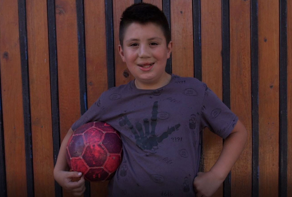 Amaro smiling and holding a soccer ball