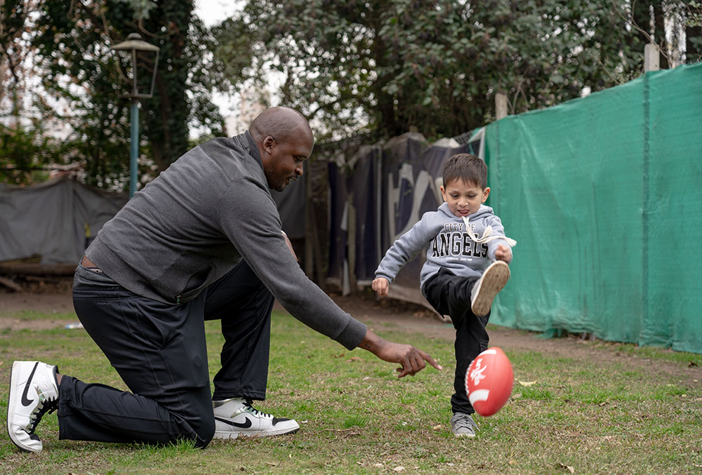 Mathias holds a football, as Benicio comes running up to kick it