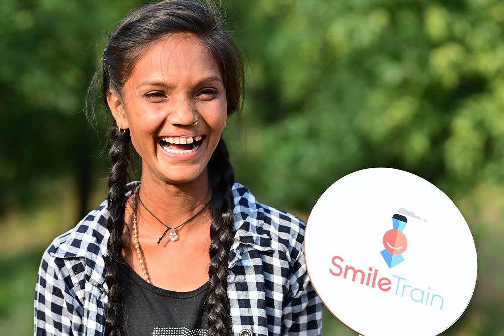 Pinki smiling and holding a Smile Train sign