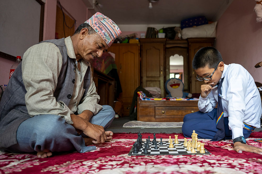 Jenious playing chess with his grandfather