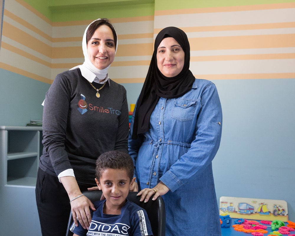 Fares sitting in front of Dr. Sally Adel and Nadia, all smiling