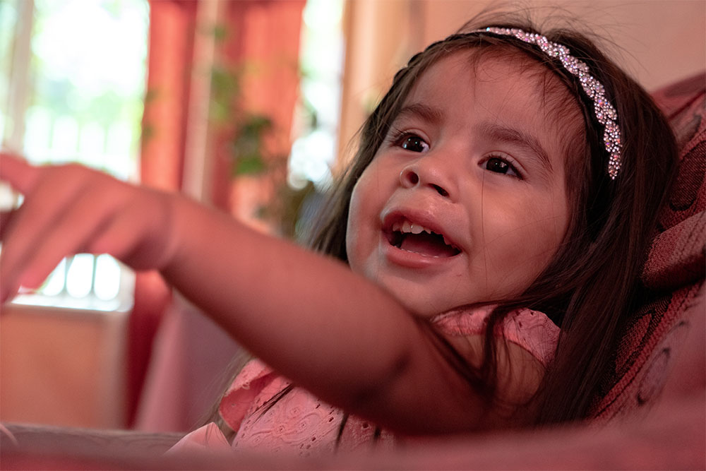 Isabella sitting in a chair, smiling and pointing