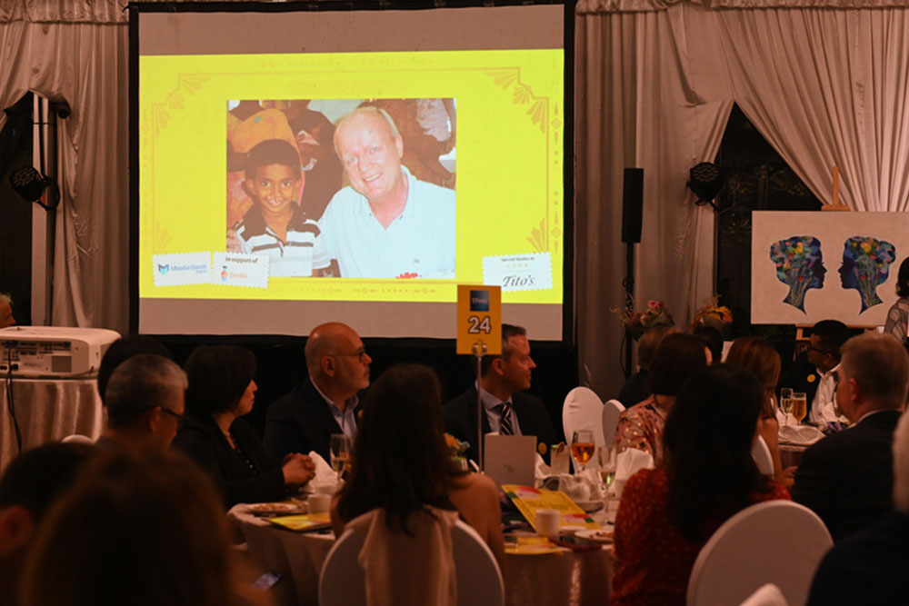 A slide featuring a picture of Martin Moodie with a Smile Train patient projected on a screen