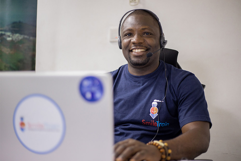 Paul Lobi smiling and helping a patients on the hotline through his laptop