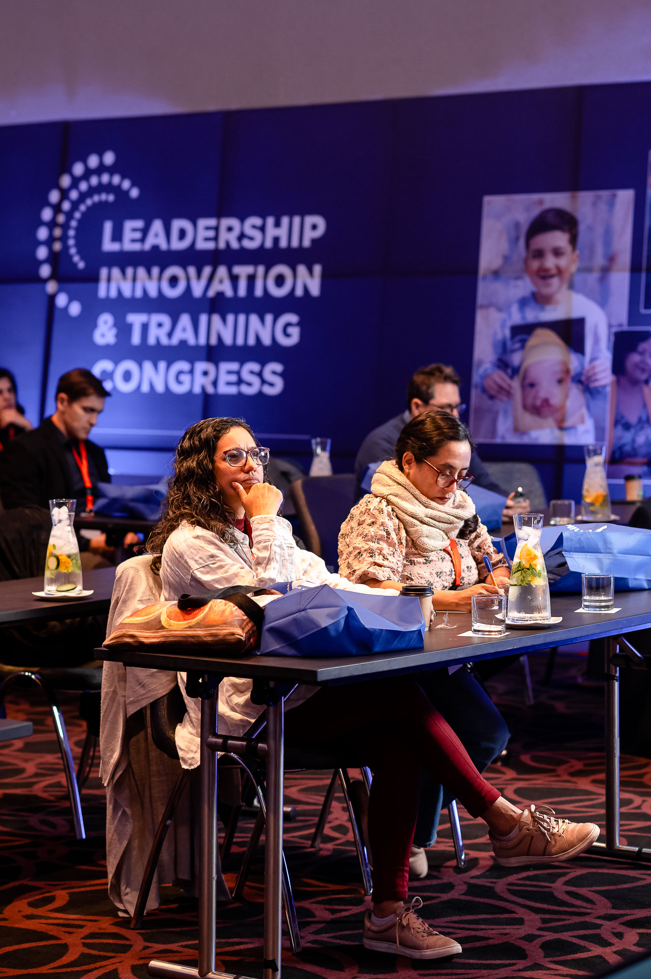 Two participants sitting at a conference table. Dr. Jerem Cruz is taking notes while the Dr. Lidia Tamayo is listening intently