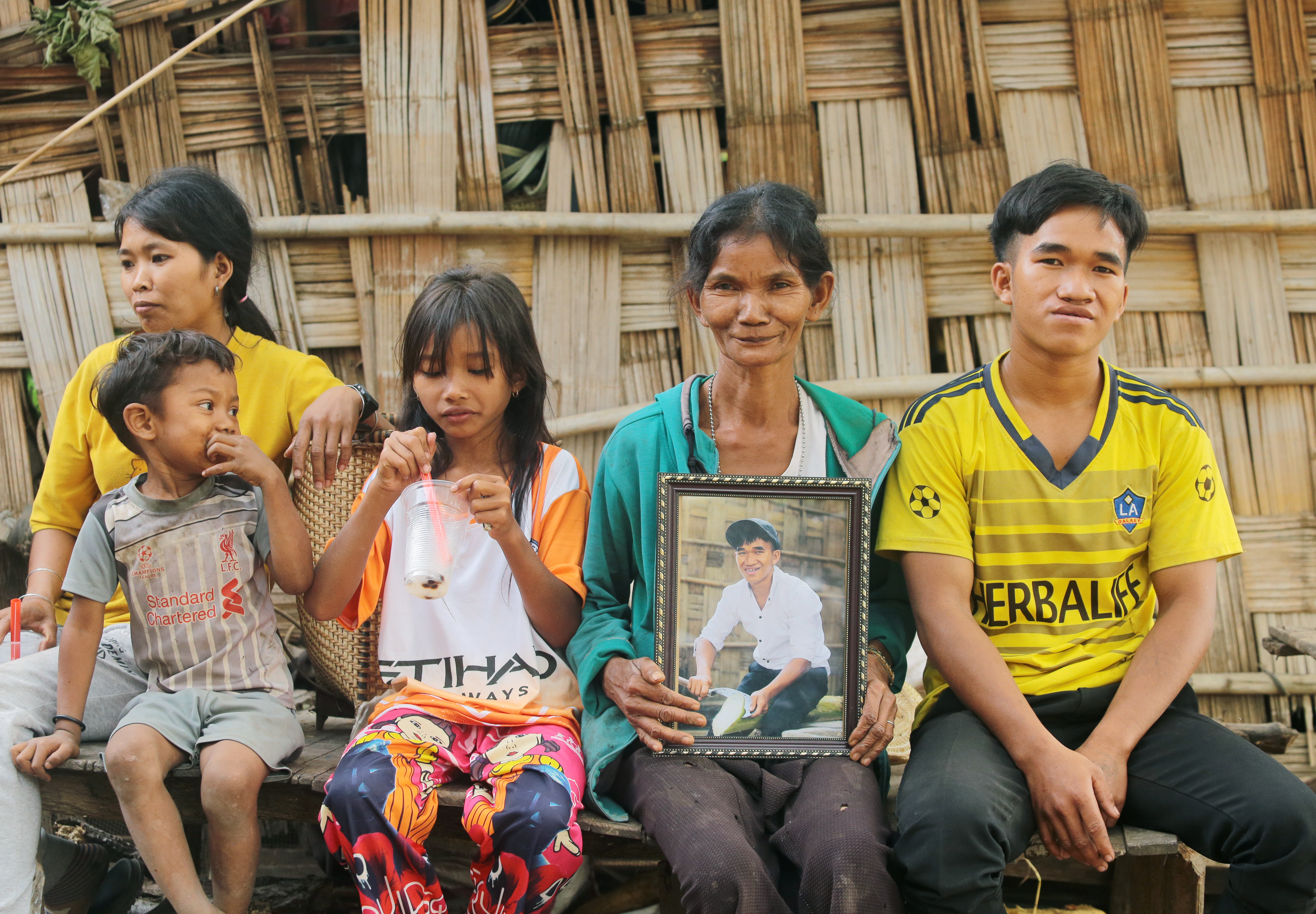 Ray and his family sitting. His mother is holding a framed photo of him after cleft surgery