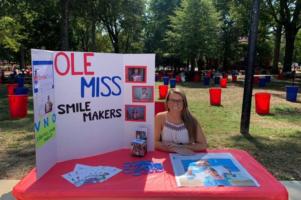 Tammy sitting at her Ole Miss Smile Makers booth on campus
