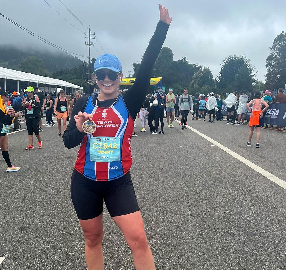 Tammy holding her medal at the finish line