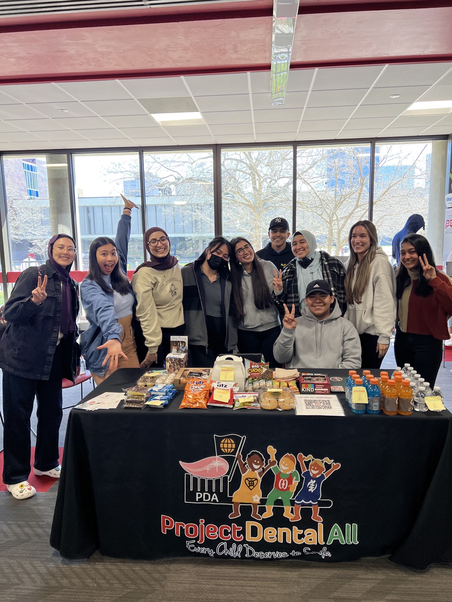 Members of Project Dental All smiling behind a bake sale table