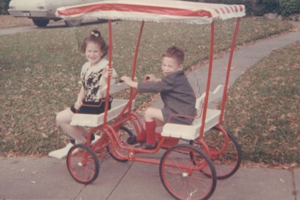 Linda and John as children riding a surrey