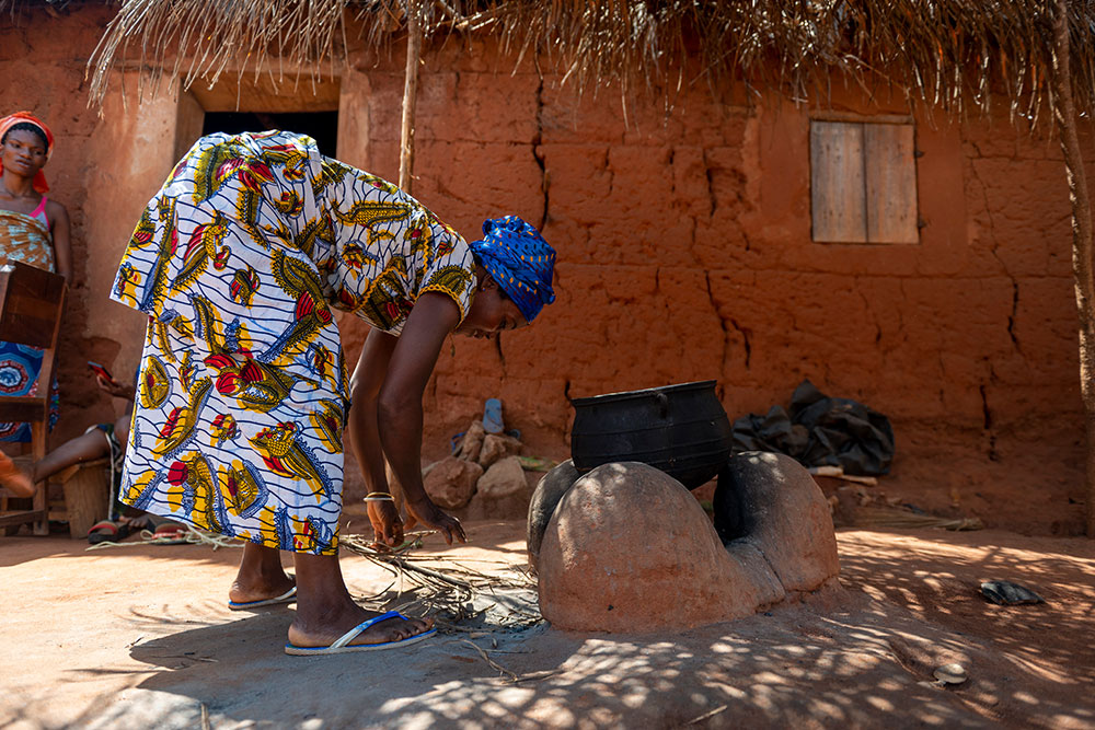 Adjoa tending a fire before cooking