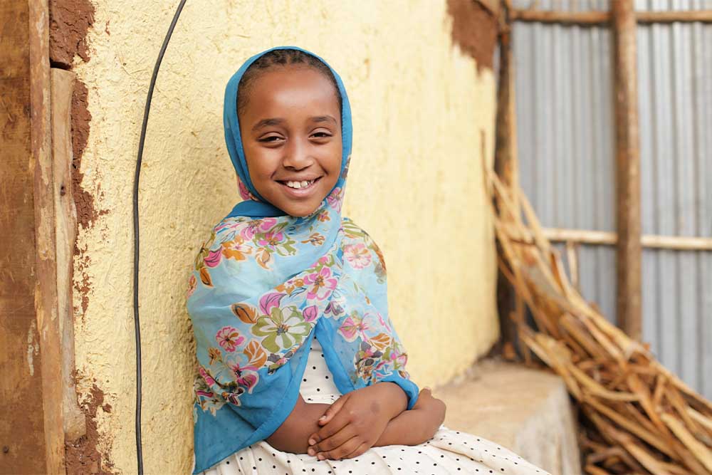 Mariam waist-up sitting on a ledge and smiling