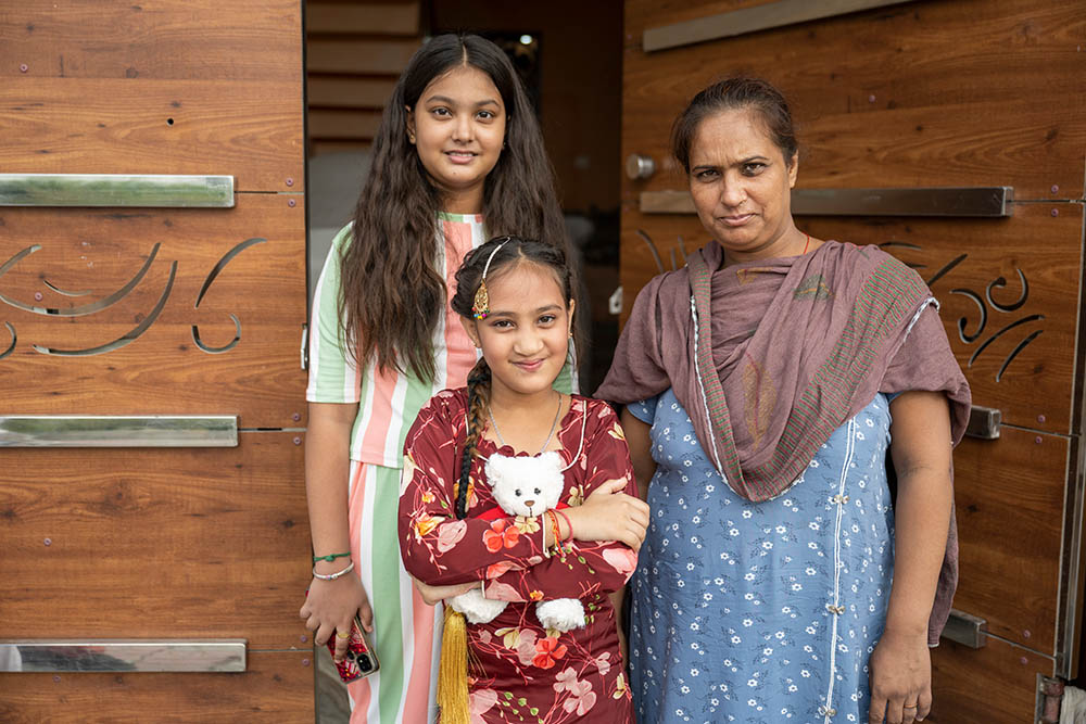Bhumika smiling and holding a Smile Train teddy bear with her sister and mother Jyoti after her cleft surgery