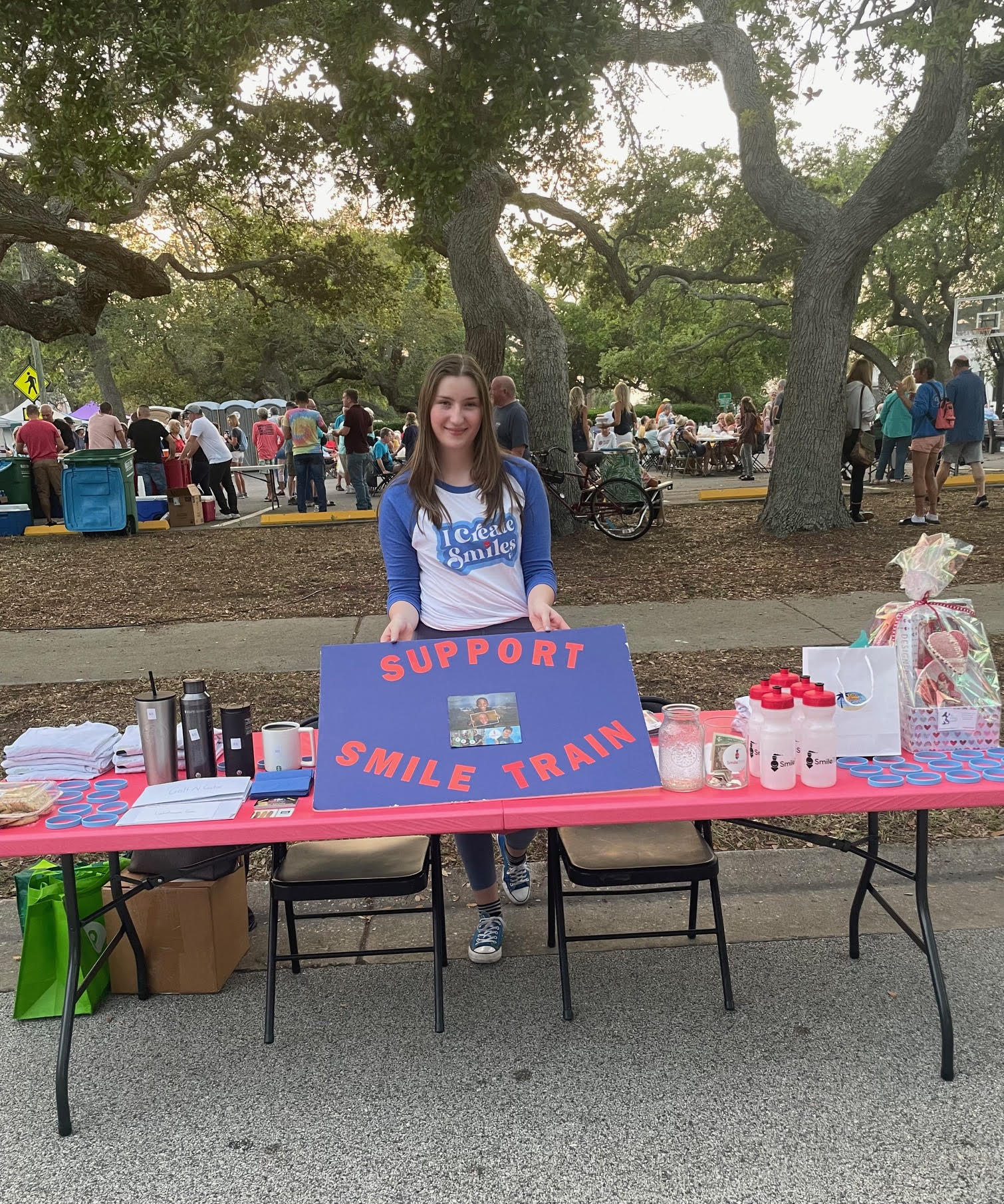 Alexandra wearing a Smile Train shirt behind a table with Smile Train merch on it
