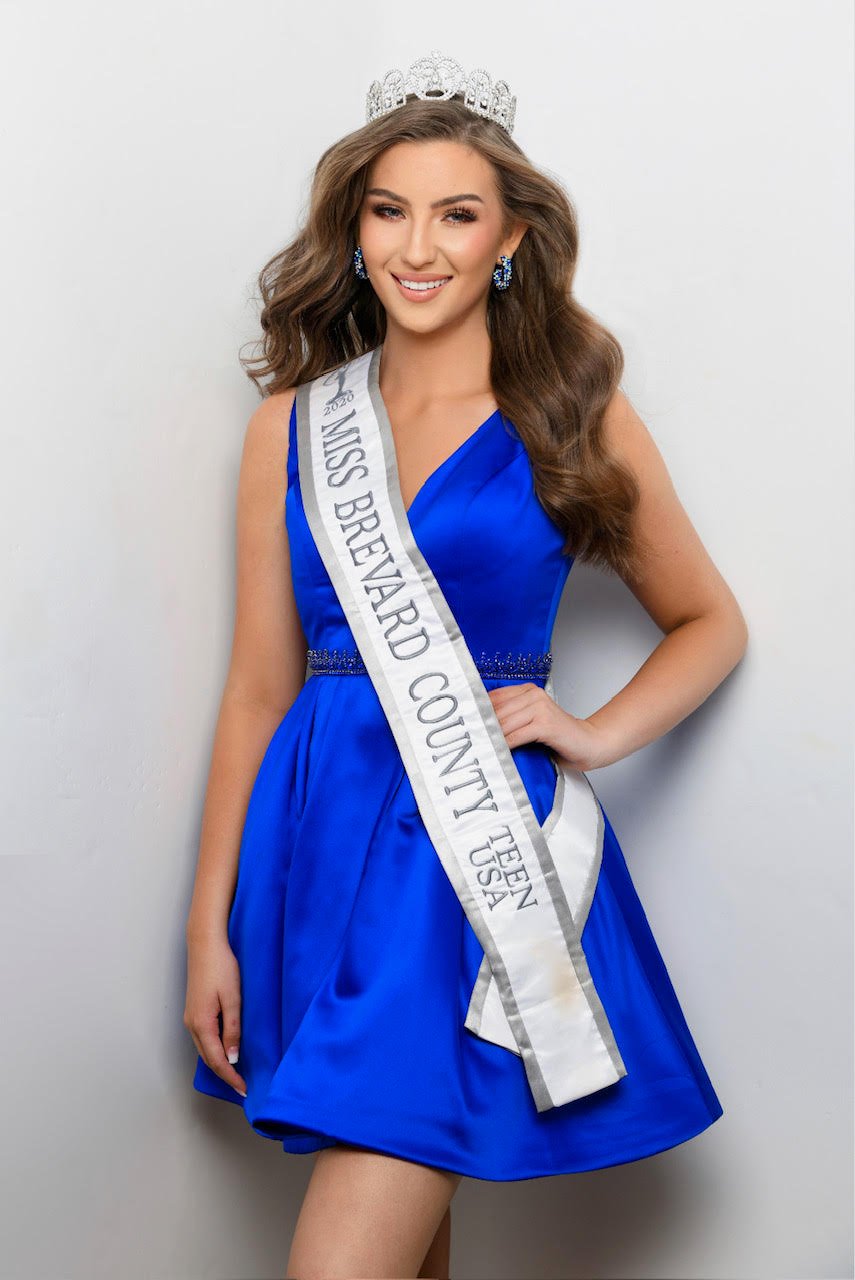 Alexandra in a blue dress and crown wearing a Miss Brevard County sash