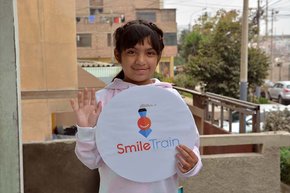 Bhania smiles and holds up a Smile Train sign