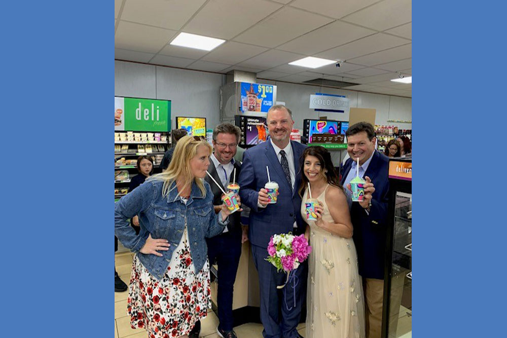 Seth and Becca at a 7-11 holding Slurpees in their wedding clothes